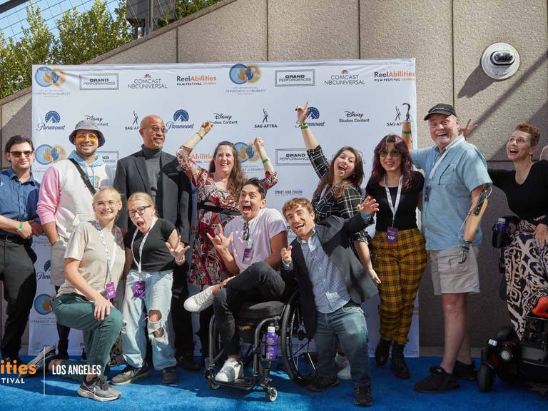 A group of the 2022 Easterseals Disability Film Challenge filmmakers and participants posing for a photo in front of the festival step-and-repeat backdrop.