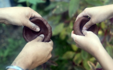 Two pairs of hands pinching a pinch pot 